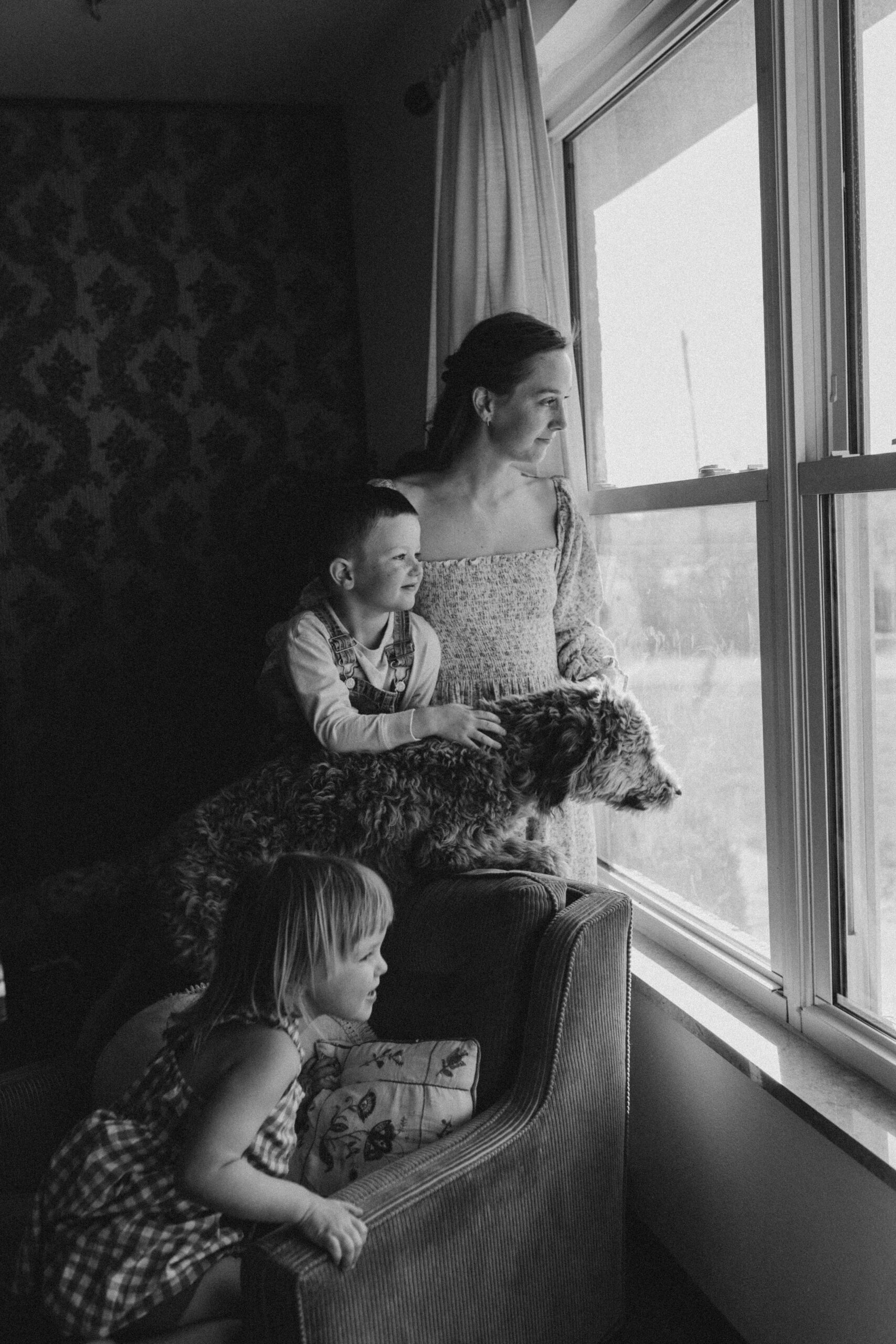 Mom and two kids look out home window