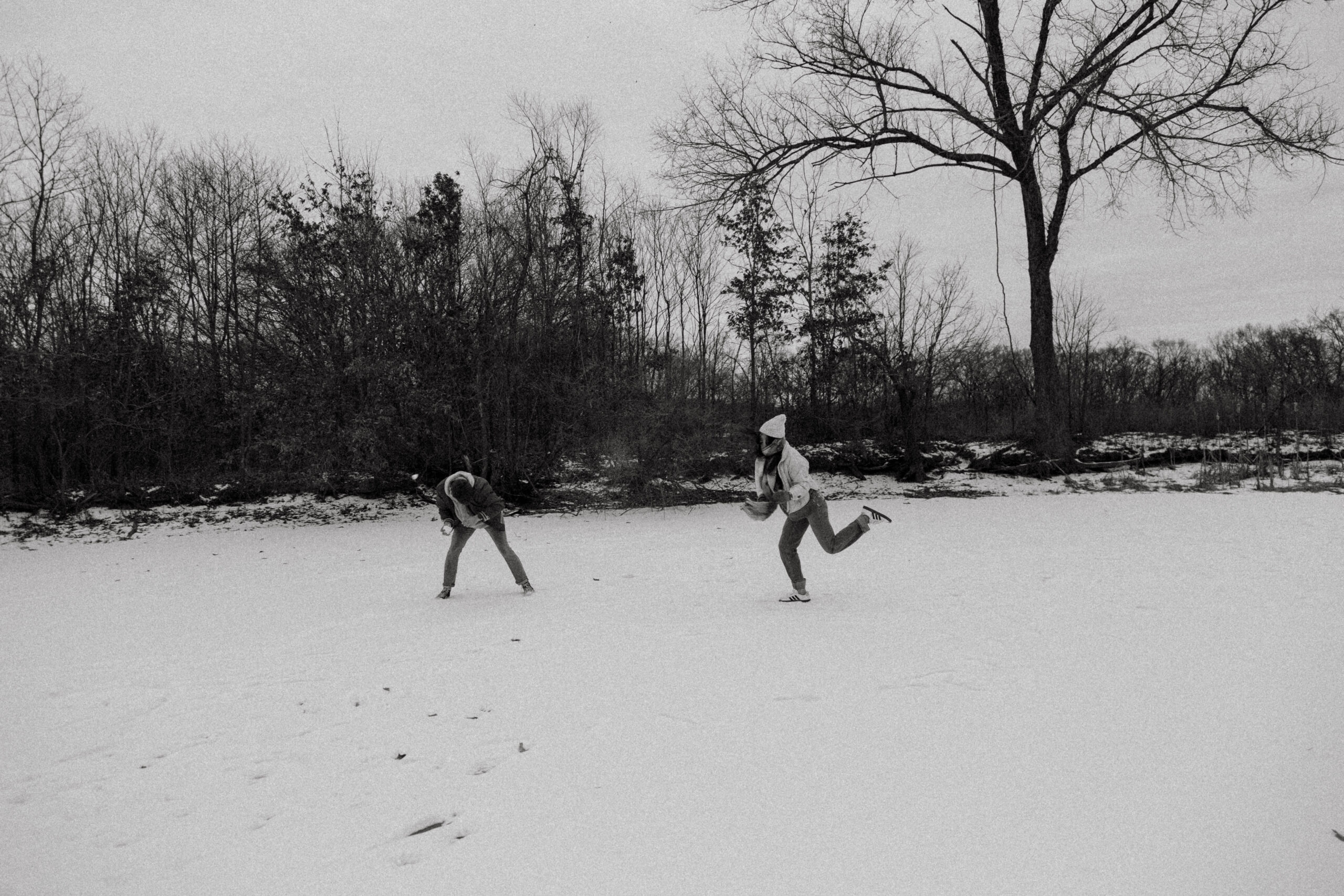 Couple having fun in the snow during a playful winter couples shoot, captured in a colorful and candid documentary style.