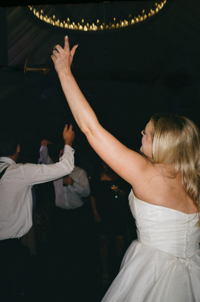 Candid dance floor shot of friends lifting the bride into the air, full of energy and joy, documentary wedding photography that tells the story of the party.