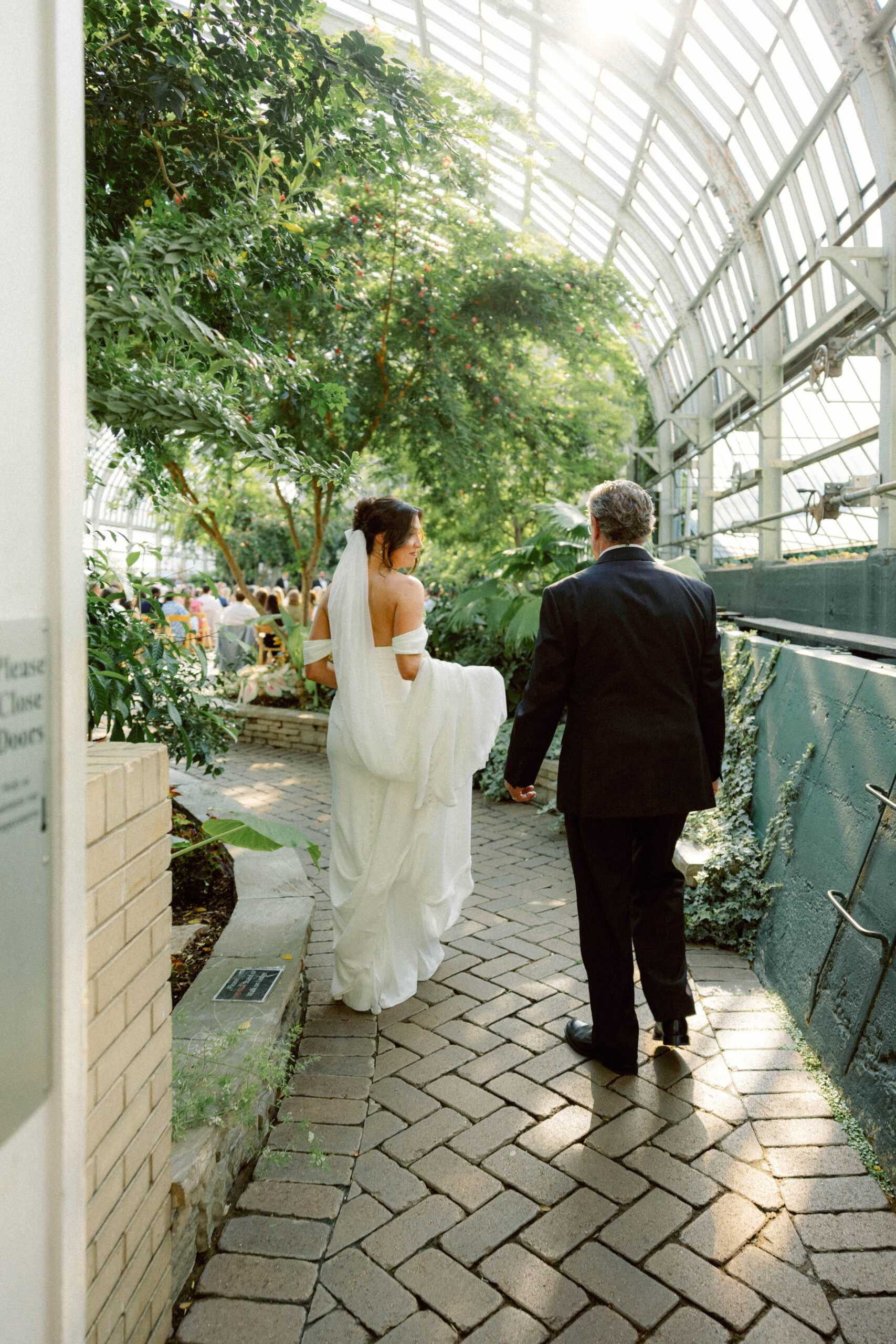 bride looks back at dad before going into ceremony space at garfield park conservatory
