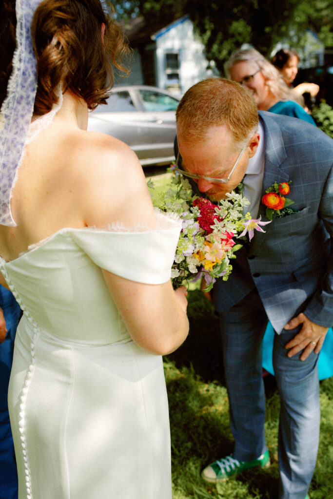 dad leans down to smell daughters bouquet from sugarberry blooms