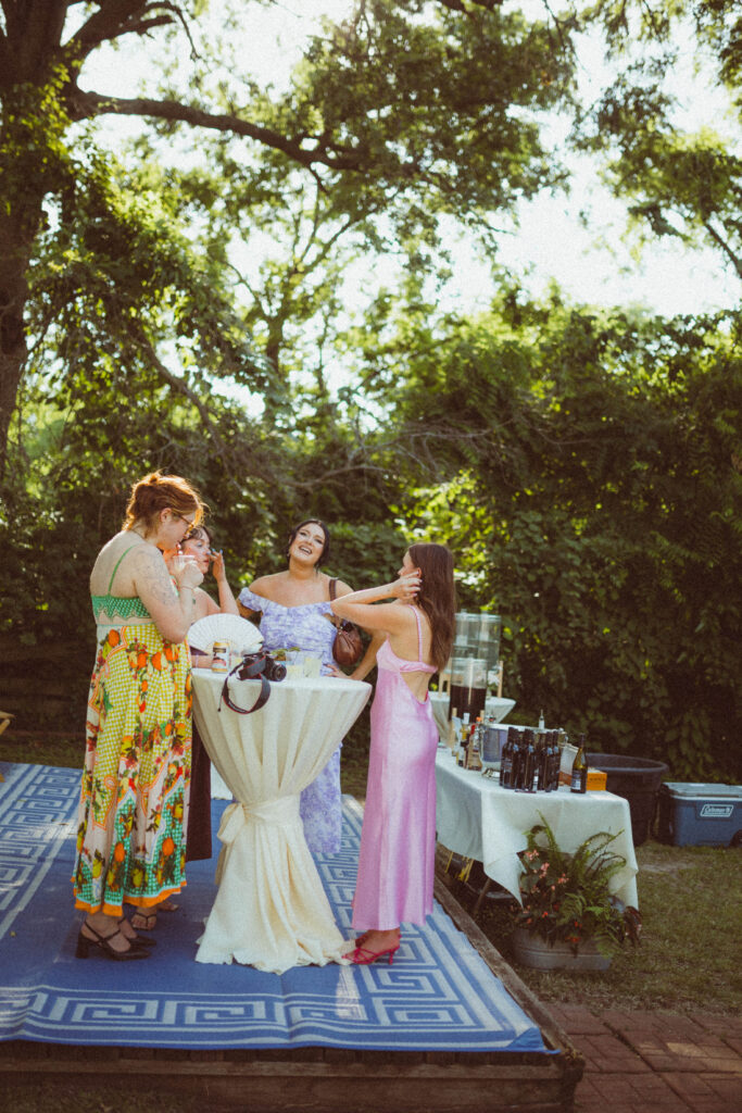 guests of wedding stand at bar smiling and laughing at elevated backyard wedding in columbia missouri