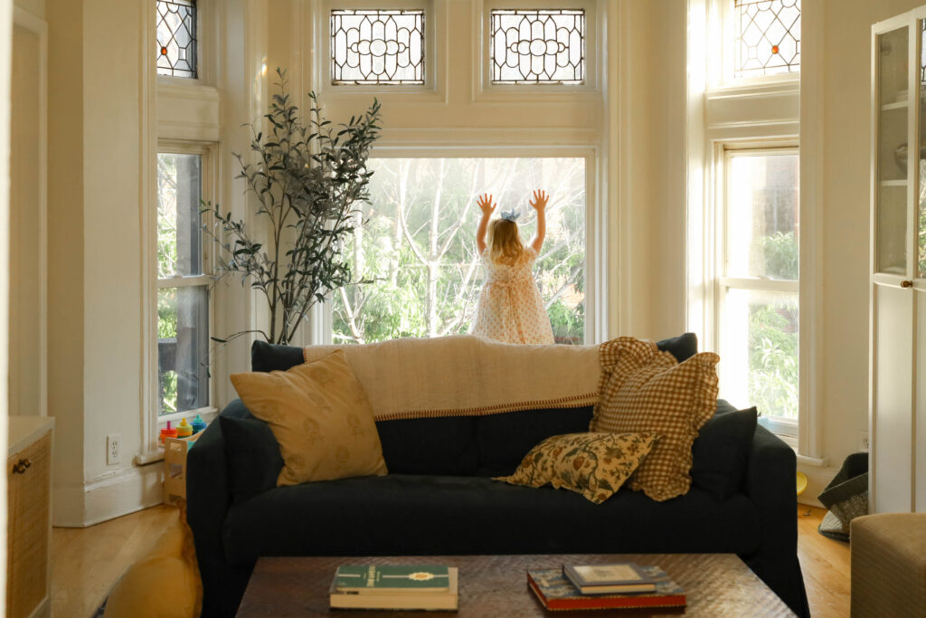 little girl looks out wide chicago apartment window during luxury documentary family session