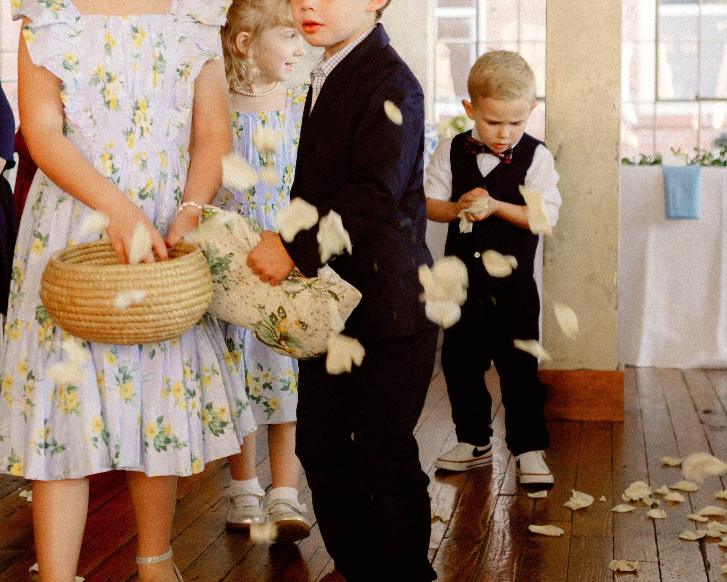 three kids tossing flower petals during ceremony – candid moment captured in loose editorial wedding photography
