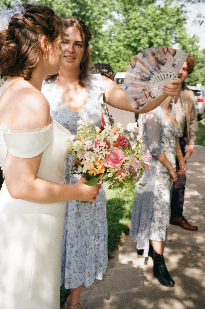 Friend fans bride before heading to ceremony at their home
Refined backyard wedding in Missouri — intimate moment with bride being fanned by friend before ceremony, photographed by Emily Ambie.